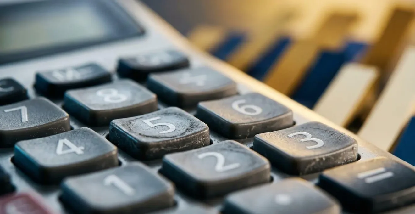 Vue macro d'une calculatrice avec graphiques de rentabilité en arrière-plan flou